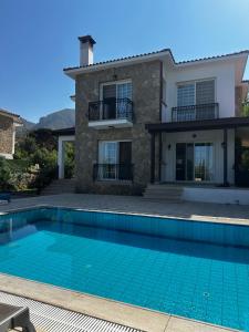 a villa with a swimming pool in front of a house at Hillside Villa with Sea Views in Kyrenia