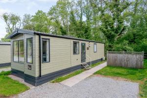 a green tiny house in a yard at Castle Brake Holiday Park in Woodbury