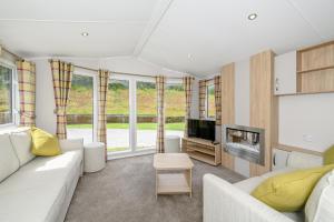 a living room with a couch and a tv at Castle Brake Holiday Park in Woodbury