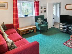 a living room with a red couch and a tv at The Cottage in Gosforth