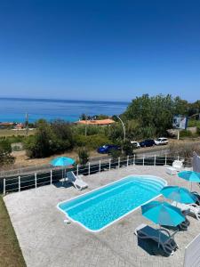 ein Swimmingpool mit Sonnenschirmen und Liegestühlen und das Meer in der Unterkunft Acrita rooftop in Zambrone