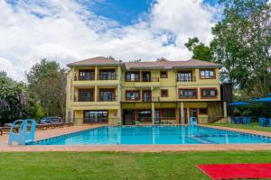 a large yellow house with a pool in front of it at Nyeri Club in Nyeri