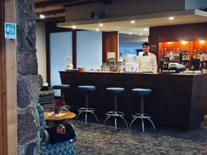 a man standing behind a bar with stools at Eurotel Cermis in Cavalese +32 photos