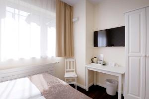 a bedroom with a bed and a desk and a tv at List Five - Your British Guesthouse in Stuttgart