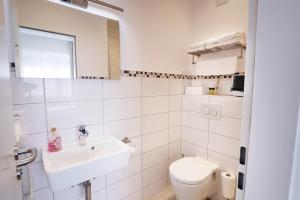 a white bathroom with a sink and a toilet at List Five - Your British Guesthouse in Stuttgart