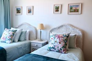 a bedroom with two wicker beds and a table with a lamp at Apartment Sapphire in Herolds Bay