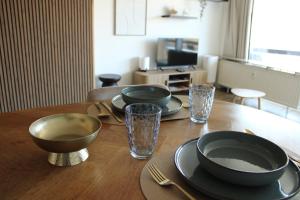 a wooden table with plates and bowls on top of it at Studio Avondzon in Blankenberge
