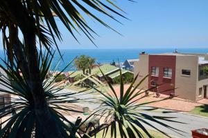 a palm tree in front of a building and the ocean at Apartment Sapphire in Herolds Bay