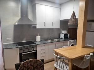 a kitchen with white cabinets and a wooden table at La Casita in Tejadillos