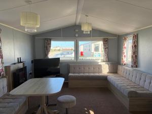 a living room with a couch and a table at PG173 Golden Palm Resort 6 Berth Caravan With Decking in Chapel Saint Leonards