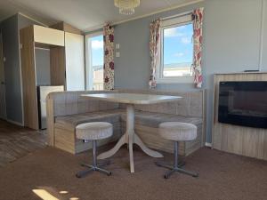 a table and two stools in a room with a fireplace at PG173 Golden Palm Resort 6 Berth Caravan With Decking in Chapel Saint Leonards