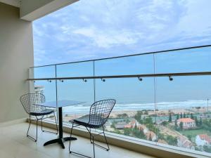 a balcony with a table and chairs and a large window at Căn hộ The Sóng Vũng Tàu Infinity Pool - Near Sea Tháp Tam Thắng in Vung Tau