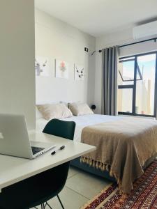 a bedroom with a bed and a desk with a laptop at Ekuku Snug in Oshakati