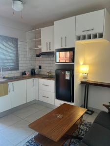 a kitchen with white cabinets and a wooden table at Ekuku Snug in Oshakati +7 photos