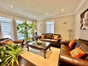 a living room with leather couches and a coffee table at Spacious 7BR Home with Private Yard & Fast WiFi! in Brampton