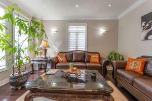 a living room with leather couches and a coffee table at Spacious 7BR Home with Private Yard & Fast WiFi! in Brampton +44 photos