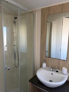 a bathroom with a white sink and a shower at PG173 Golden Palm Resort 6 Berth Caravan With Decking in Chapel Saint Leonards