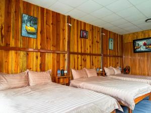 two beds in a room with wooden walls at Bungalow Scent in Da Lat
