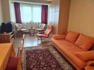 a living room with an orange couch and chairs at Nelly Apartman in Gheorgheni