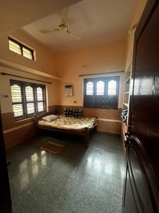 a bedroom with a bed and two windows at Sri Devi Krupa in Hubli