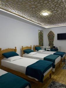 a room with three beds with blue pillows at Olimxon Guest House in Bukhara