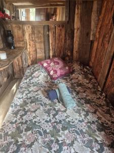 a small bed in a wooden room with a floral bed sidx sidx sidx at Cabane en Cévennes in Saint-Germain-de-Calberte