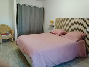 a bedroom with a large bed with pink sheets and pillows at Ty Véron, labellisé PMR in Asnières-la-Giraud