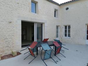 a group of chairs around a table in front of a building at Ty Véron, labellisé PMR in Asnières-la-Giraud