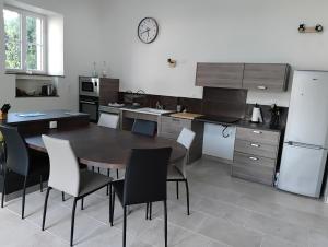 a kitchen with a table and chairs and a clock on the wall at Ty Véron, labellisé PMR in Asnières-la-Giraud