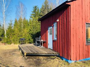 a red building with a wooden deck with a table on it at Väikse haldja onn in Majala