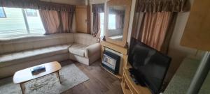 a living room with a television and a couch at Towyn Happy Days K3 in Rowen