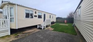 a white tiny house parked next to a building at Towyn Happy Days S7 in Rowen +12 photos