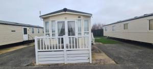 a small house with a white gate in a parking lot at Towyn Happy Days S7 in Rowen