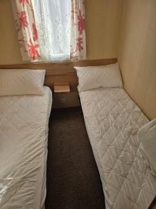 two beds in a small room with a window at Towyn Winkups F07 in Rowen +19 photos