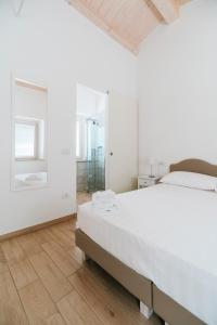 a white bedroom with a large bed and a mirror at Il Conventino 46 in Falconara Marittima
