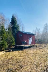 a red shed with a porch in a field at Väikse haldja onn in Majala