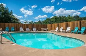 a swimming pool with chairs and a fence at Private Sauna Cabin Sleeps 34 Game Rooms in Pigeon Forge