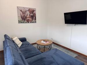 a living room with a blue couch and a table at Ben Lomond Apartment - Macaulay Letting in Alexandria