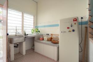 a small kitchen with a sink and a refrigerator at Tido Home, private queen room w bathroom, shared public area in Ipoh