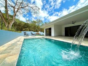 a swimming pool with a waterfall in a house at Coral Breeze in Puntarenas