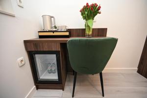 een bureau met een groene stoel en een vaas met bloemen bij Laurea Rooms in Split