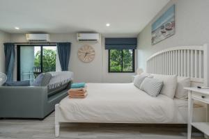 a bedroom with a bed and a couch and a clock at Cozy Studio Apartment E414 in Phuket +27 photos