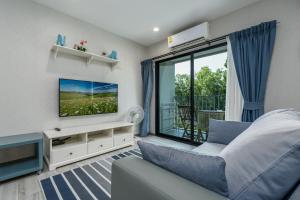 a living room with a blue couch and a tv at Cozy Studio Apartment E414 in Phuket