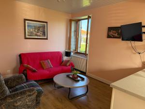 a living room with a red couch and a table at gite de Sauviat 25 chemin du grand Pacher le bourg de Sauviat 63120 in Sauviat