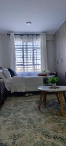 a bedroom with a large bed and a table at BlueByMis Studio Apartment in Muchatha