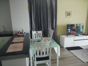 a dining room with a glass table and a kitchen at Aisyah Studio D perdana in Kota Bharu