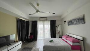 a bedroom with a bed with pink pillows and a ceiling fan at Aisyah Studio D perdana in Kota Bharu