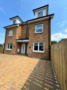 a brick house with a fence in front of it at Inchcailloch Townhouse, Loch Lomond in Bonhill