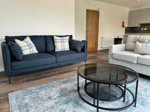 a living room with a blue couch and a glass table at Inchfad Apartment 2/1 in Bonhill +3 photos