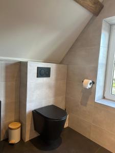 a bathroom with a black toilet and a window at Op t hiem in Nes